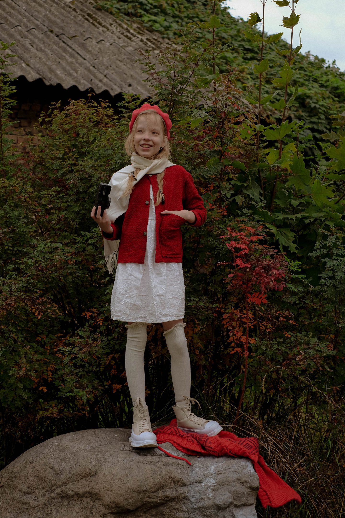 Child in a red cardigan in an overgrown garden